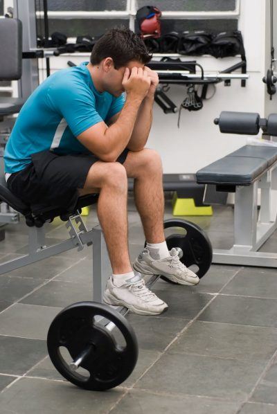 Man with head down in weight room