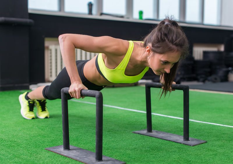 Young Fit Woman Doing Horizontal Push Ups With Bars In Gym.